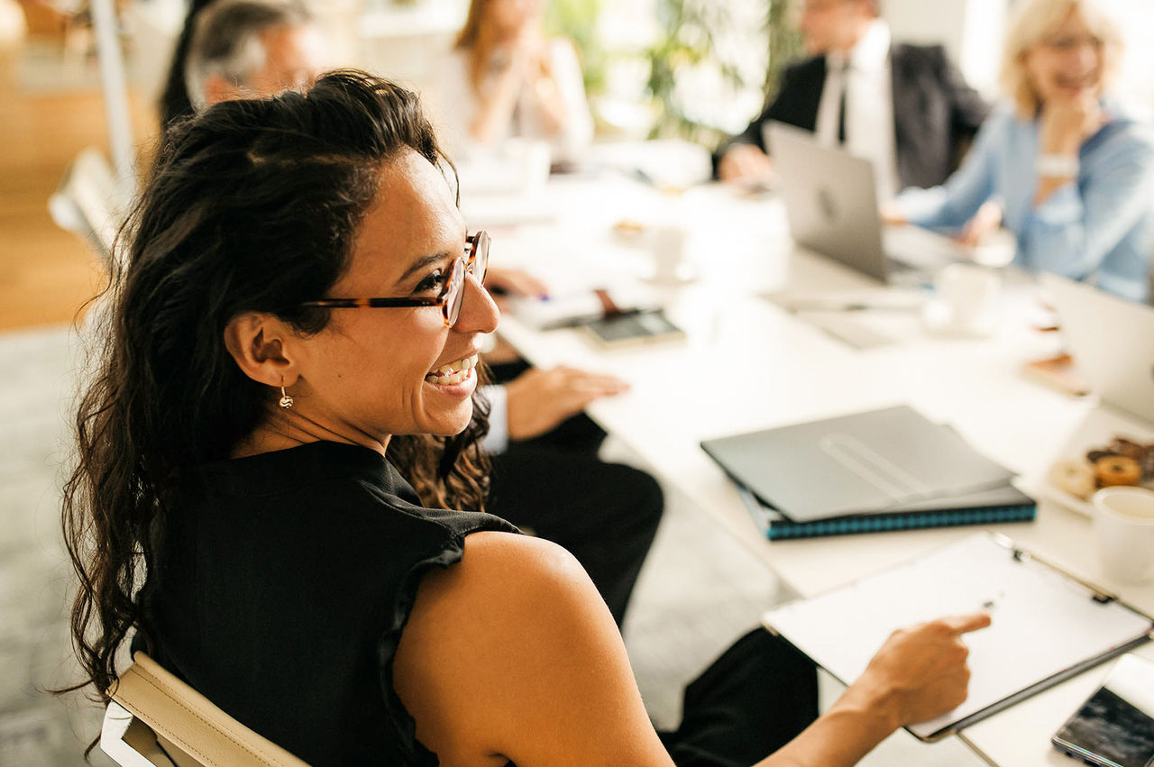 An executive laughing with her colleagues during a strategy meeting. 