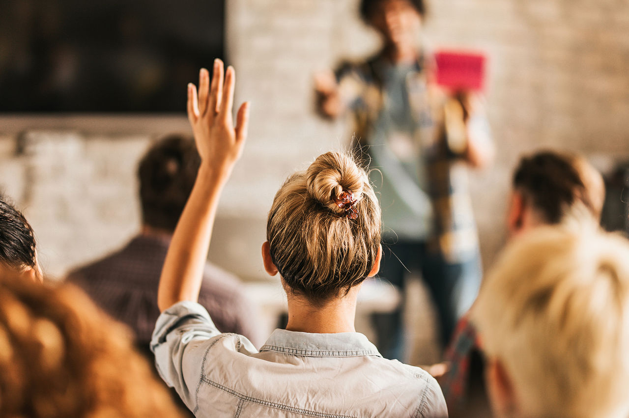Woman raising her hand in a classroom. 