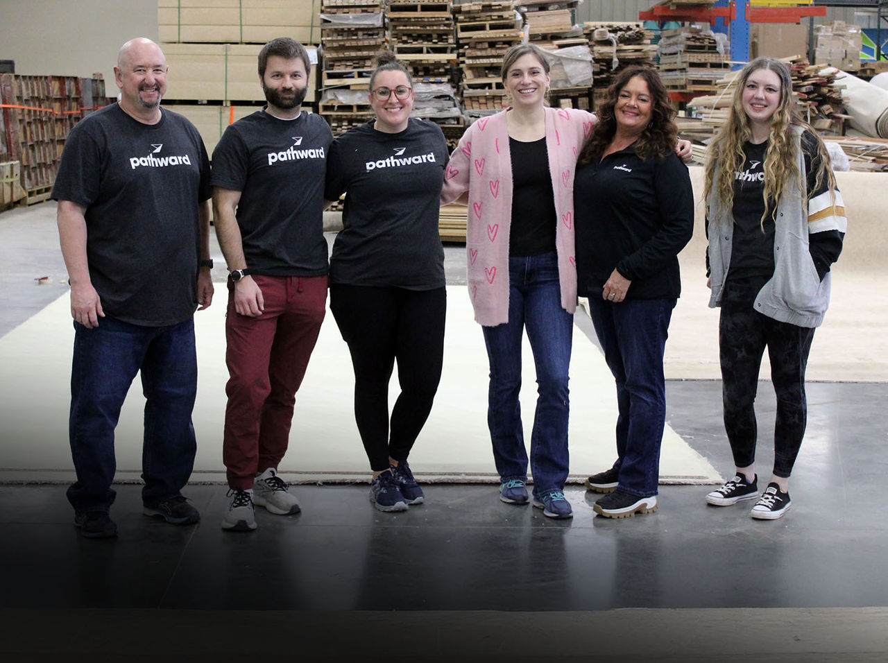 Smiling volunteers packing cans into a cardboard box.
