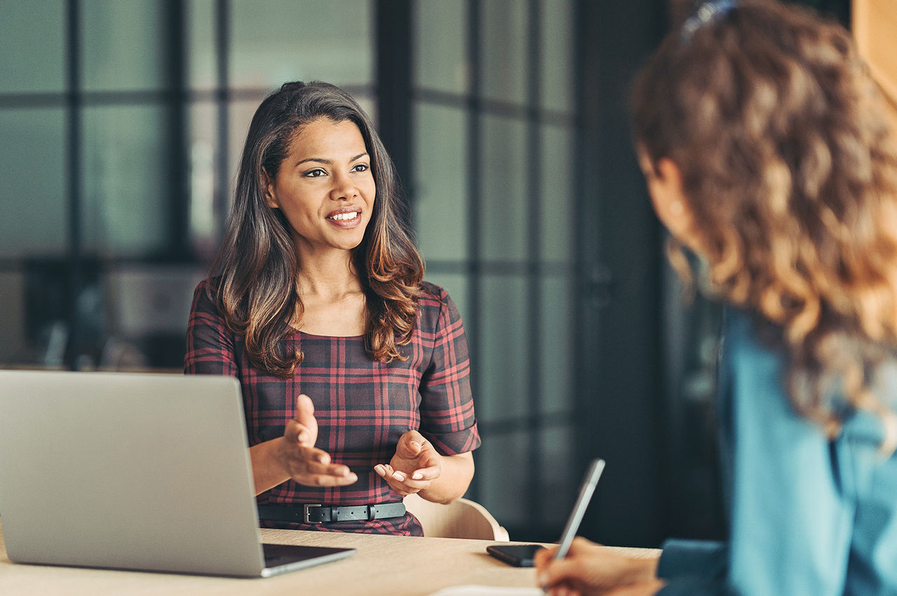 Seated woman with a laptop computer describing a BaaS solution to a customer.