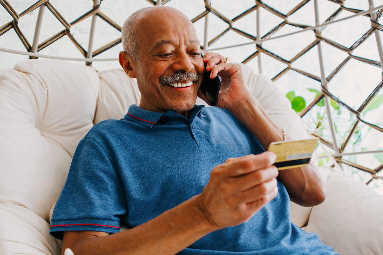Older gentelman on the phone while holiding his prepaid card