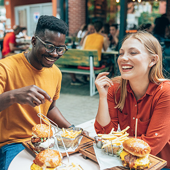 Friends eating burgers and fries and have fun in outdoor restaurant