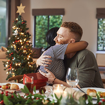 Shot of young friends opening their gifts together while having Christmas lunch at home