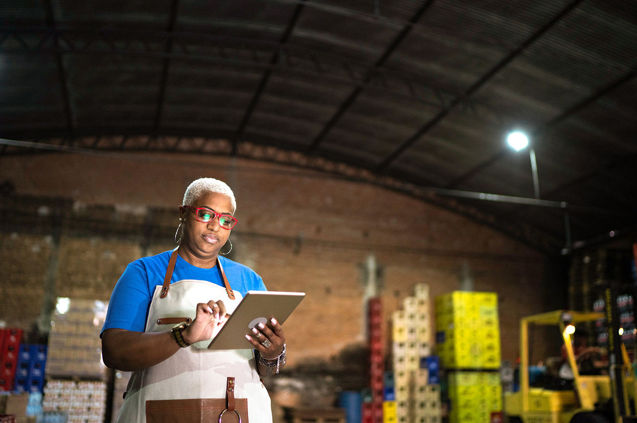 Woman in a warehouse viewing inventory on tablet.